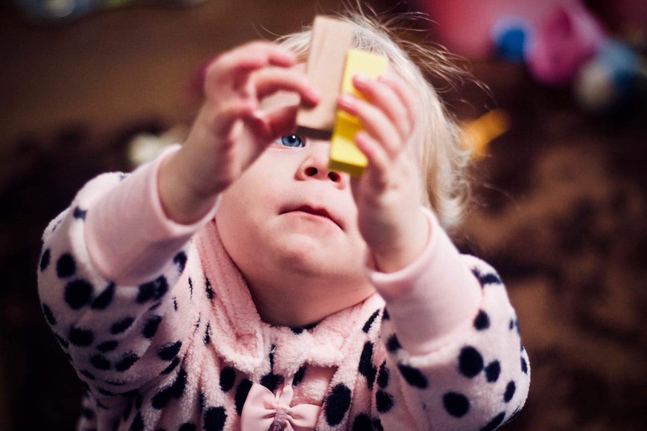 A small child absorbed in play with simple wooden blocks, warm natural light